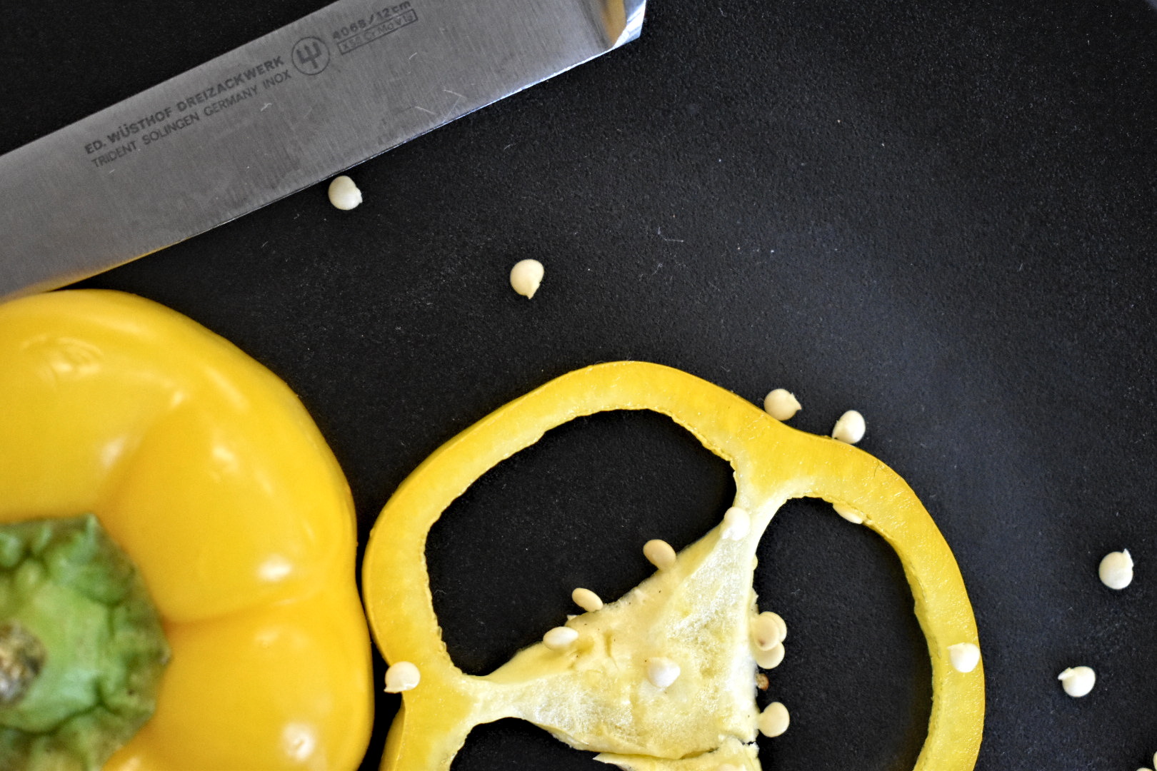gelbe Paprikascheibe und Schneidemesser auf schwarzem Hintergrund