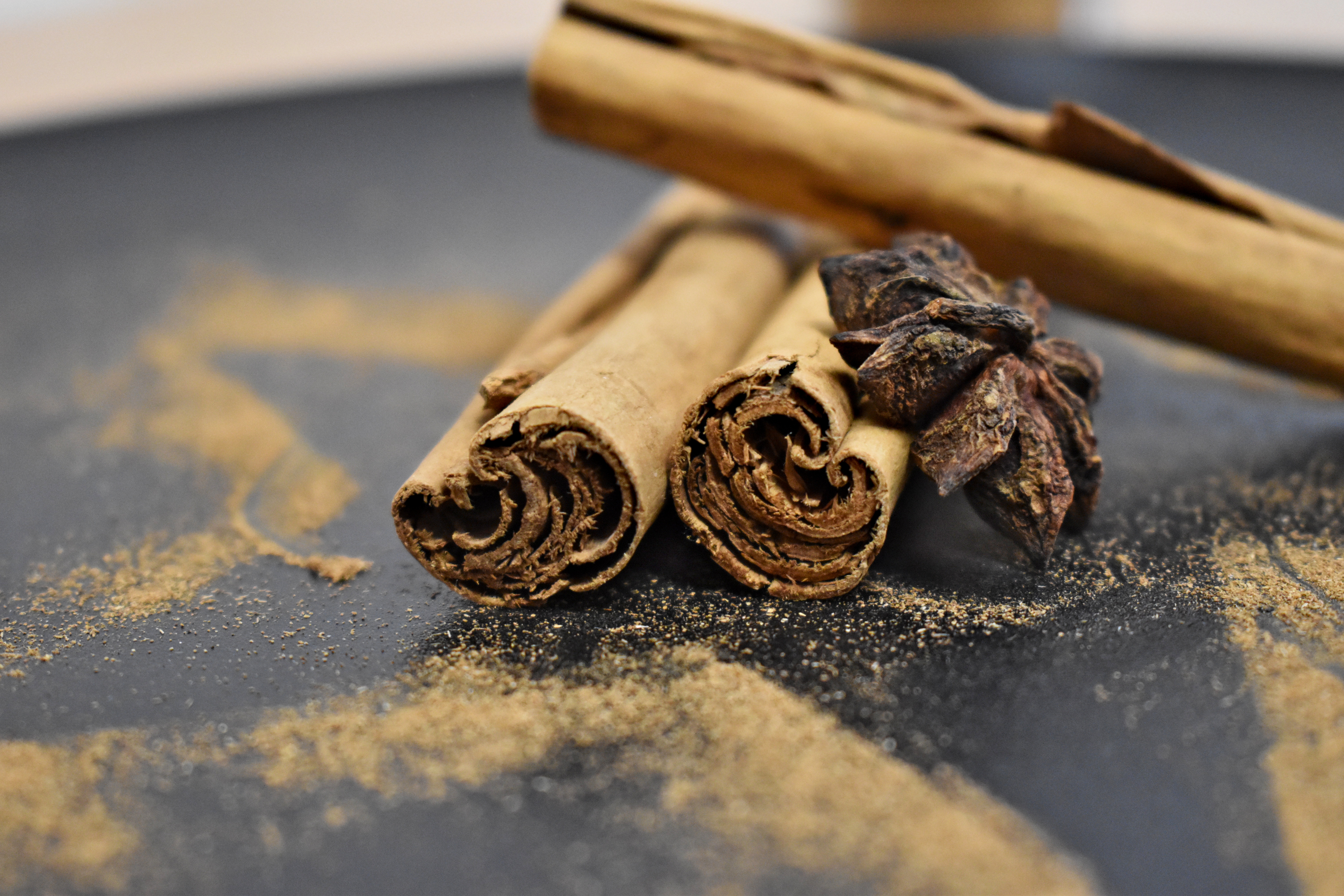 Diese Seite ist eine Fotogalerie aus sechs Bildern. Auf allen sind zwischen drei und fünf Zimtstangen und zwei Sternanis, welche umgeben von Zimtpulver auf einer schwarzen Steinplatte liegen, zu sehen.>
	    <img class=